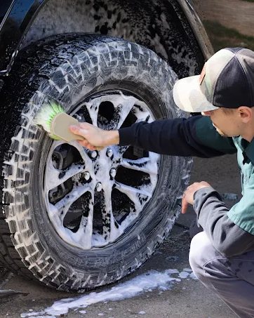 Scrubbing a tire with foam and a detailing brush